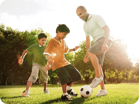 Father playing soccer with his two sons on a sunny afternoon